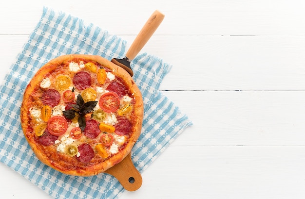 Italienische Pizza Peperoni mit Salami und Käse auf rustikalem hölzernem weißem Hintergrund