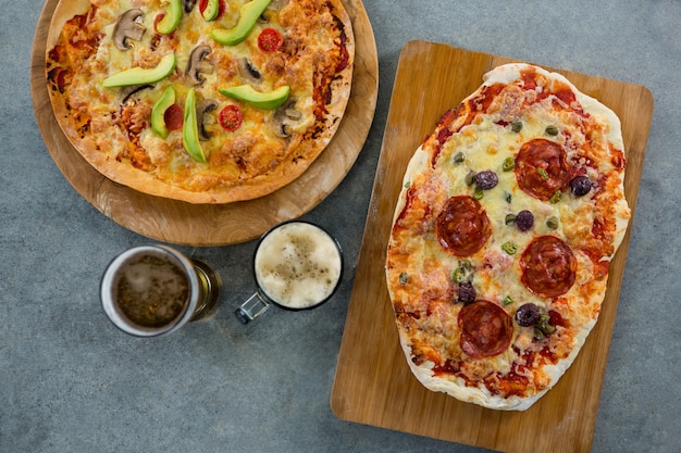 Italienische Pizza serviert auf einem Schneidebrett mit Bierkrug und Glas