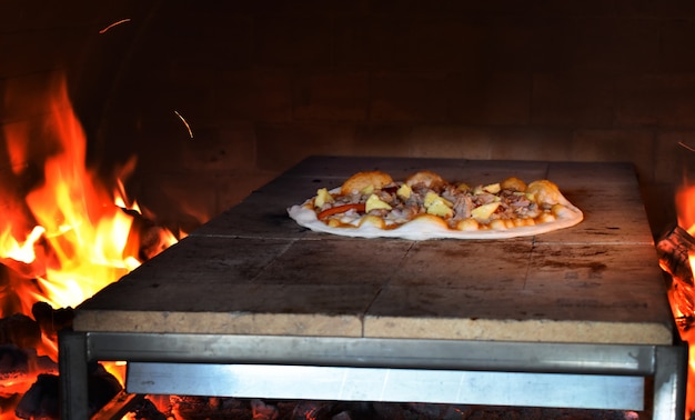 Foto italienische pizza wird in einem traditionellen holzofen zubereitet