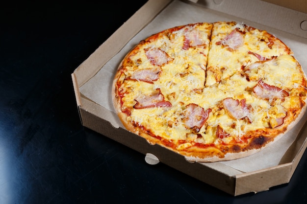 Italienische Pizzalieferung. Köstliches ofengebackenes Pizzeriagericht mit Mozzarella, Parmesan und Käse, geliefert in einem Karton. Leckeres Fast Food zum Mitnehmen, das zum Abendessen im Ofen zubereitet wird.