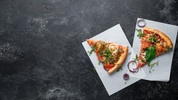Italienische Pizzastücke auf dunklem Hintergrund mit Spinat