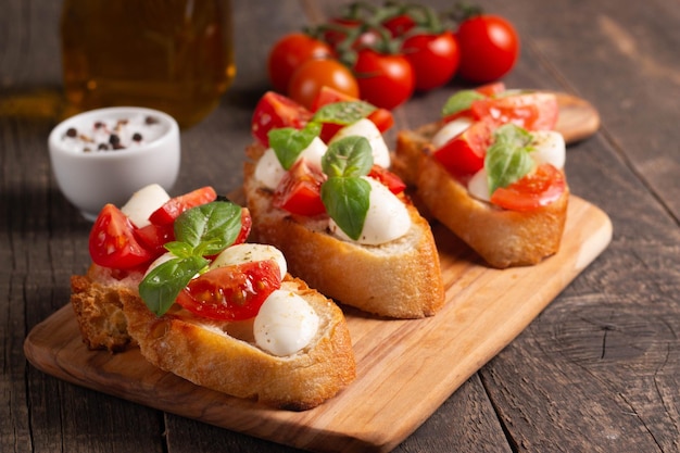 Italienische Tomaten-Käse-Bruschetta-Tapas-Antipasti mit gehackten Gemüsekräutern und Öl