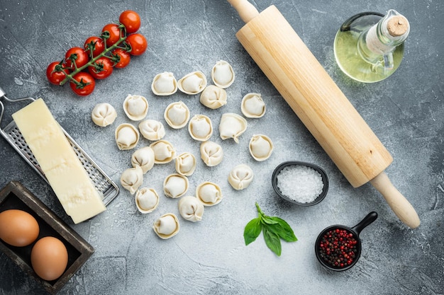 Italienische Tortellini mit frischen Ricottablättern und Tomaten, auf grauem Hintergrund, Draufsicht flach