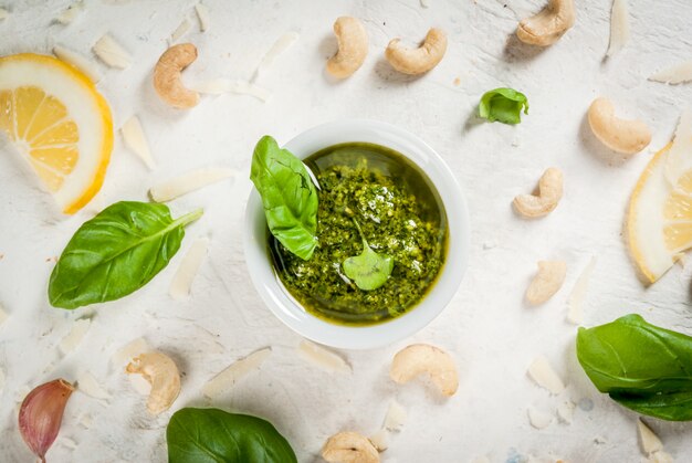 Italienische und mediterrane Küche Pesto-Sauce mit Zutaten auf einem weißen Steintisch: Parmesankäse-Cashewnüsse-Butter-Zitronen-Basilikum