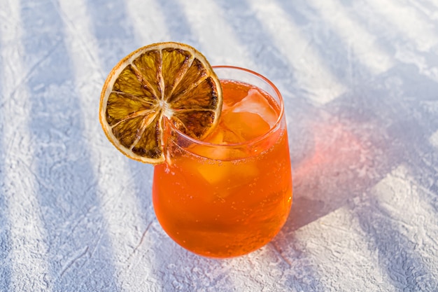 Italienischer Aperol Spritz Alkohol Cocktail mit Eiswürfeln und getrockneter Orangenscheibe