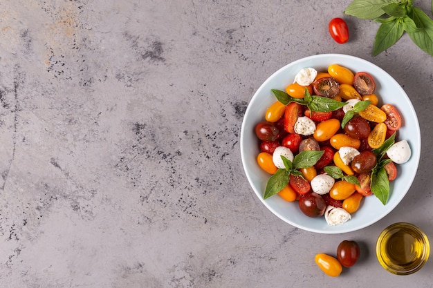 Italienischer Caprese-Salat mit Tomaten, Mozzarella-Käse, Basilikum, Olivenöl, Draufsicht.