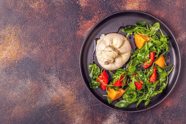 Italienischer Käse Burrata mit frischem Rucola, Tomaten, Olivenöl