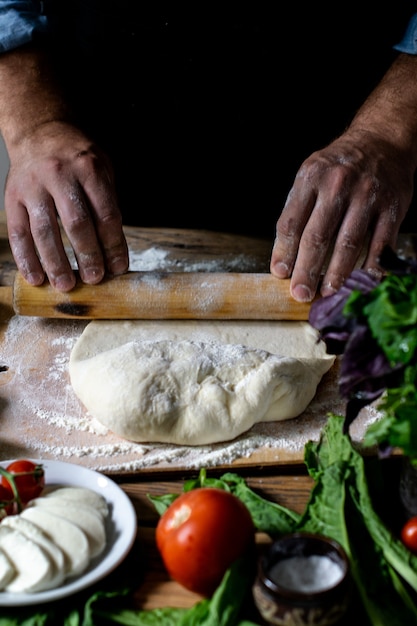 Foto italienischer koch kocht pizzamannhände, die pizzateig für pizzahände des kochkochs kochen