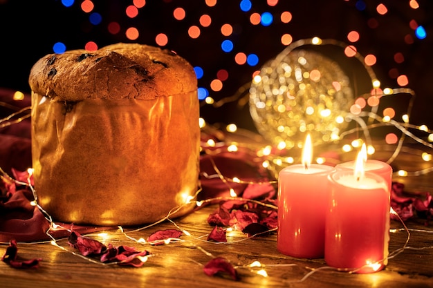 Italienischer Kuchen Panettone und rote Kerzen in weihnachtlichem Ambiente