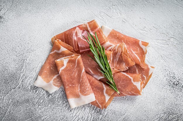 Italienischer Schinken-Crudo-Parmaschinken auf einem Tisch. weißer Tisch. Draufsicht.