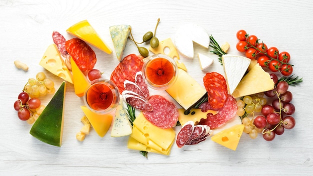 Italienisches Antipasti-Wein-Snack-Set. Käsesorte, Salami und Trauben auf weißem Holzhintergrund. Italienische Küche. Ansicht von oben. Freiraum für Ihren Text.