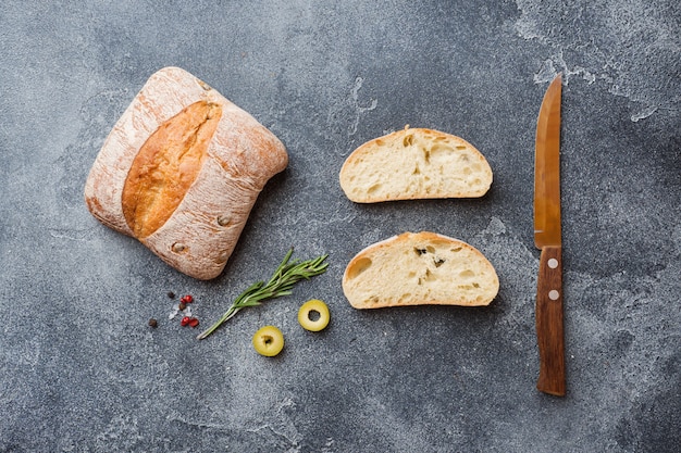 Italienisches ciabatta Brot mit Oliven und Rosmarin auf einem dunklen konkreten Hintergrund