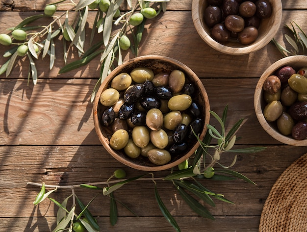 Italienisches Essen, mit Paprika und grünen Oliven, gefüllt mit Käse, schwarzen Oliven, Olivenöl auf Holztisch