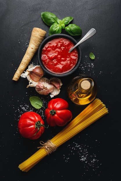 Italienisches Essen mit Spaghetti-Gemüse und Tomatensauce auf dunklem Tisch. Draufsicht.