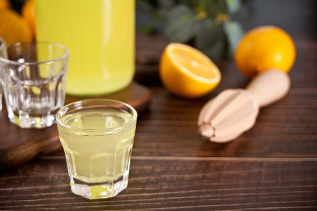 Italienisches Getränk Zitronenlikör Limoncello in einer Flasche und leeren Gläsern auf dem Holztisch.