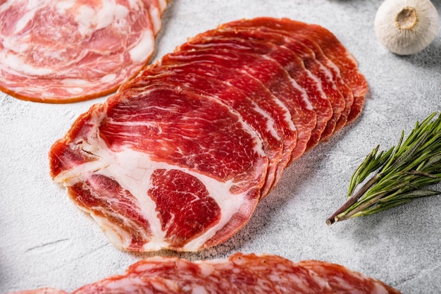 Italienisches, in Scheiben geschnittenes Coppa-Fleisch auf grauem Steintischhintergrund