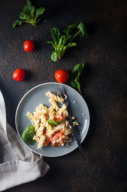 Italienisches Nudelgericht, das mit gebackenem Feta-Käse und Tomaten auf dunklem Hintergrund mischt. Fetapasta.