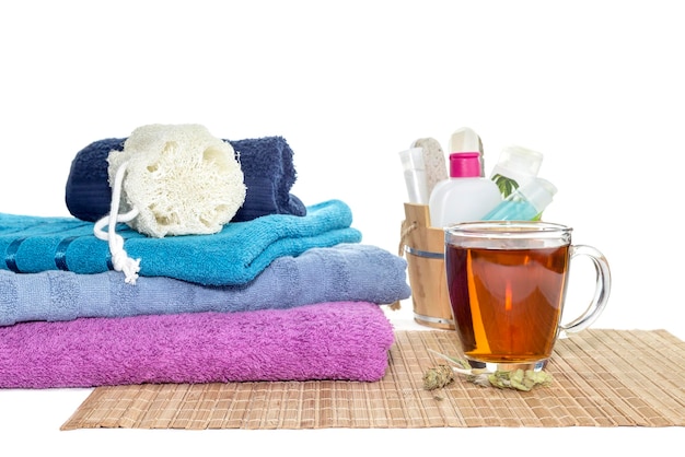 Itens de higiene pessoal toalhas de cores diferentes e uma xícara de chá quente perfumado sobre fundo branco