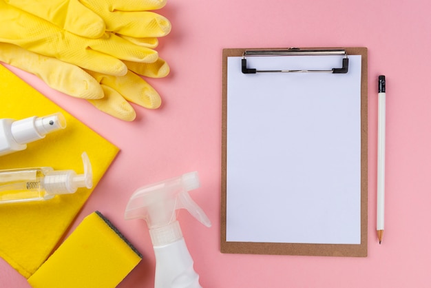 Itens de limpeza completos na parede rosa com o bloco de notas branco. Conceito de limpeza.