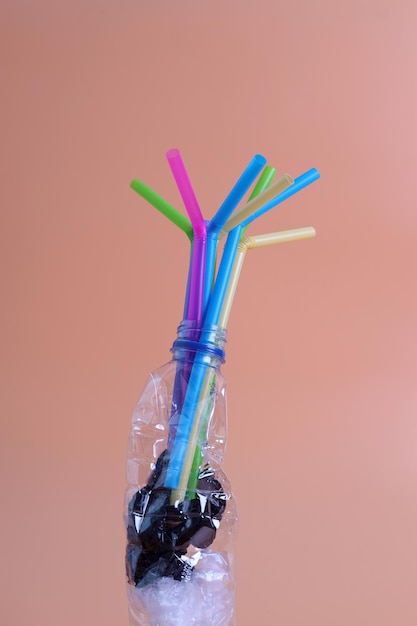 Itens de plástico de uso único para uso doméstico, incluindo garrafas de água, sacos, canudos em fundo pastel. Conce