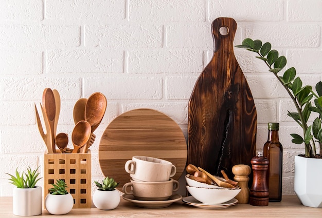 Itens ecologicamente corretos de utensílios de mesa modernos na bancada de madeira da cozinha contra os materiais amigáveis da parede de tijolos brancos sem plástico