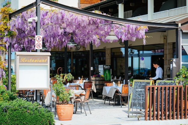 Izola, Eslovenia - 24 de abril de 2018: Entrada con flores púrpuras de glicina en el restaurante de la calle en la ciudad vieja de Izola, Eslovenia