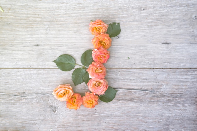 J, rosenblumenalphabet lokalisiert auf grauem hölzernem hintergrund, flache lage