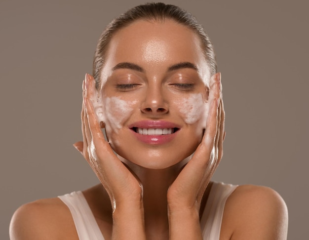 Jabón de lavado de mascarilla facial de mujer cerca de la piel limpia. fondo de color