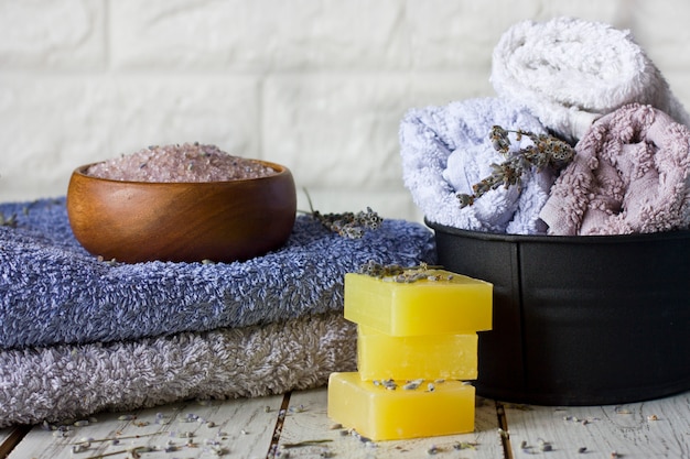 Jabón de lavanda natural y sal de baño, aceite francés y toallas sobre un fondo de madera blanco