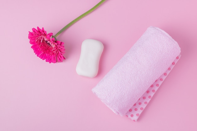 Foto jabón de manos antibacteriano, toalla y flor sobre un fondo rosa