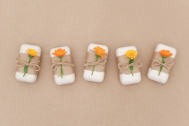 Foto jabón natural hecho a mano decorado con papel artesanal, flagelo y flores de caléndula naranja. cosmética orgánica, cero residuos,