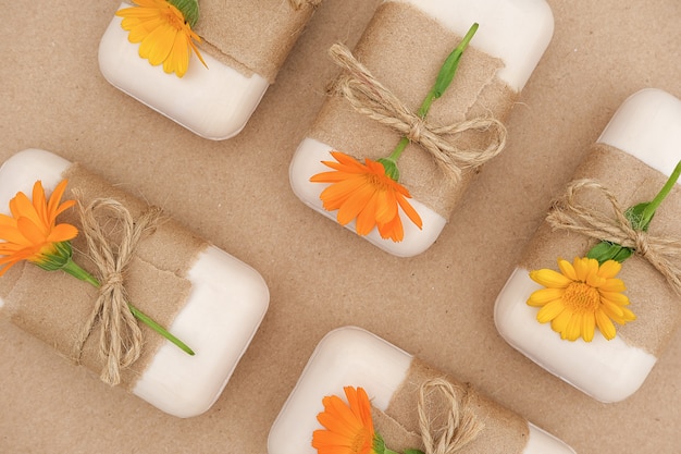 Foto jabón natural hecho a mano decorado con papel artesanal, flagelo y flores de caléndula naranja.