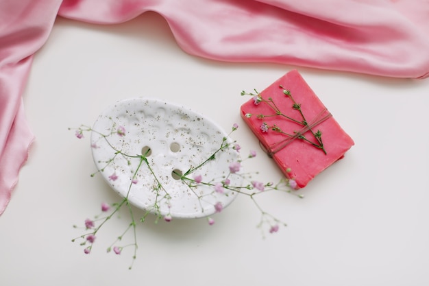 Jabón natural hecho a mano con plato de cerámica y vestido rosa plateado. productos cosméticos naturales spa