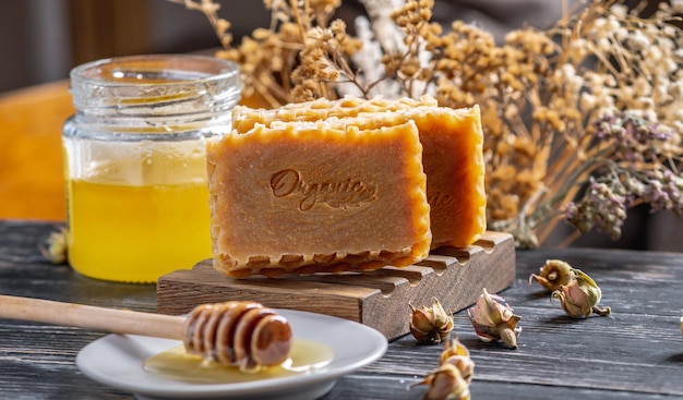 Jabón natural de miel hecho a mano con la inscripción Jarra de jabonera de madera orgánica de miel y palo de miel sobre la mesa
