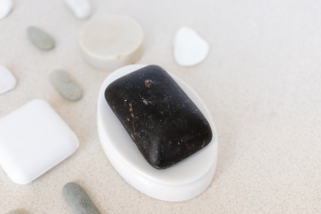 Jabón natural negro en una jabonera con piedras de mar