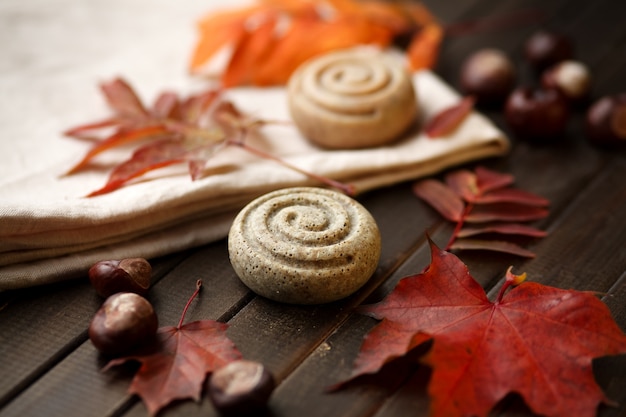 Foto jabones orgánicos en el lino contra hojas de otoño y fondo de madera, de cerca