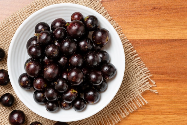 Jabuticaba in der Schüssel auf Jute - Draufsicht. Jaboticaba oder Jabuticaba ist der einheimische brasilianische Weinbaum. Art Plinia Cauliflora. Brasilianische Beere.