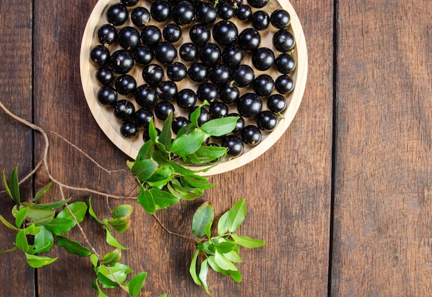 Jabuticaba, Jabuticabas frisch geerntet in Töpfen und Körben auf rustikalem Holz angeordnet, Ansicht von oben.