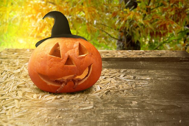 Jack-o-Lantern com chapéu e minhocas na mesa de madeira com fundo da floresta