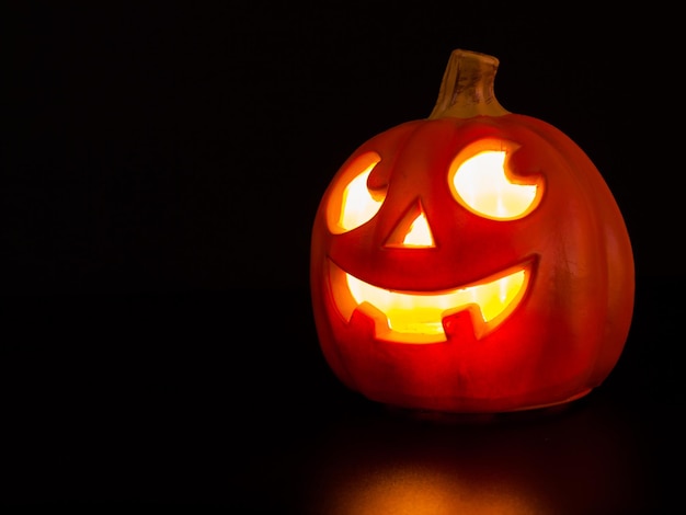 Jack-o'-lantern iluminado sobre fondo negro.