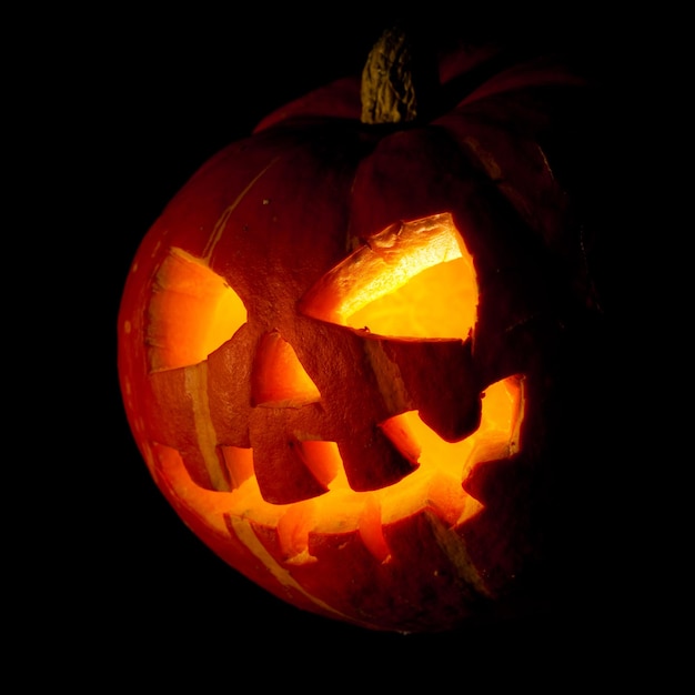 Jack-o-lantern viejo y aterrador sobre fondo negro.