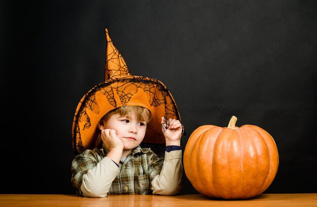 Jack o linterna niño pequeño en sombrero de bruja con preparación de calabaza de halloween niño de vacaciones de halloween