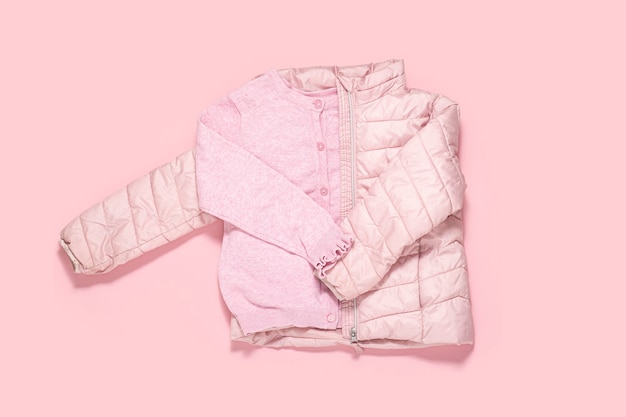 Jacke und Bluse für Kinder für ein Mädchen auf rosa Hintergrund. Ansicht von oben, flach.