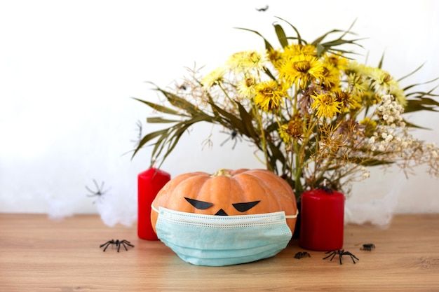 JackoLantern com máscara médica flores secas e velas vermelhas em fundo branco Abóbora de Halloween