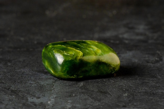 Jade verde mineral de piedra sobre un fondo de hormigón negro El concepto de uso de minerales y cristales en astrología y medicina alternativa o complementaria