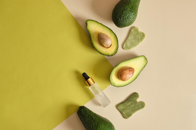 Jadeit-Gua-Sha-Schaber und frische ganze und geschnittene Avocado-Massage mit Avocado-Öl-Konzept