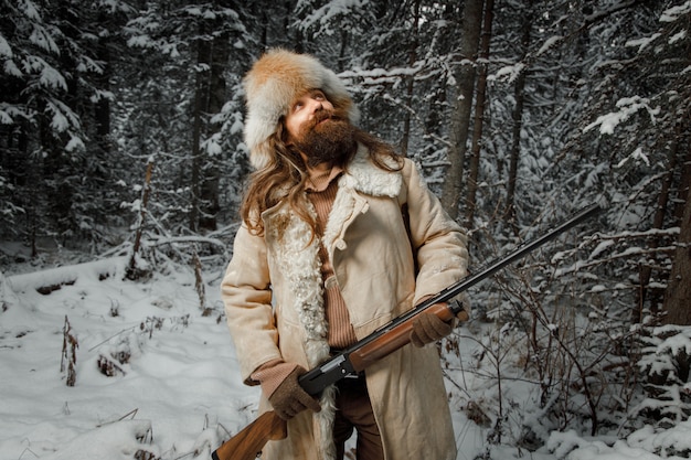 Jäger im Winter Vintage Kleidung mit Bart im Wald mit Pistole