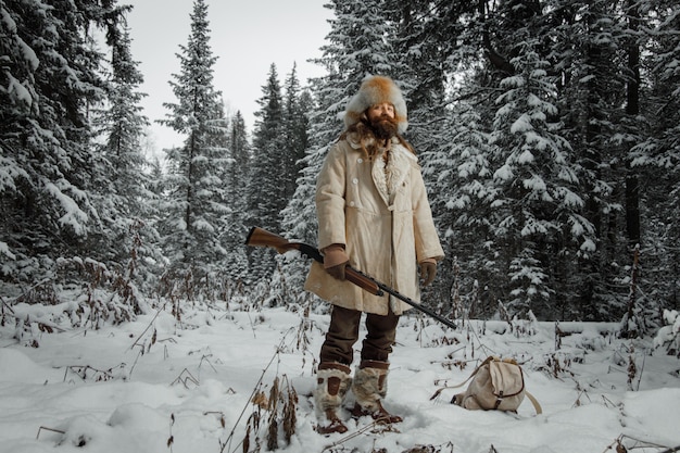 Jäger in Vintage-Kleidung mit Pistole schleicht durch den Wald