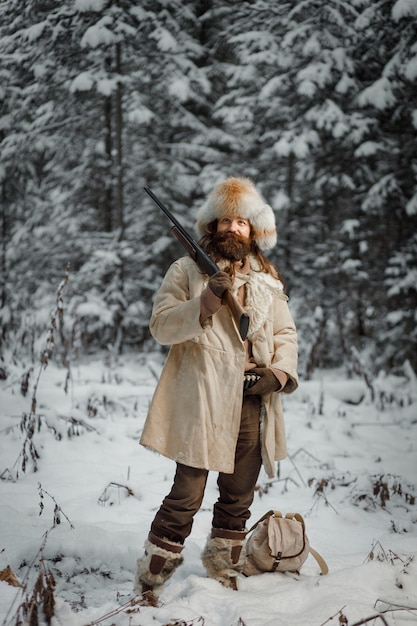 Jäger in Vintage-Kleidung mit Pistole schleicht durch den Wald