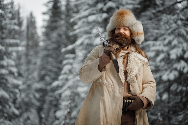 Jäger in Vintage-Kleidung mit Pistole schleicht durch den Wald